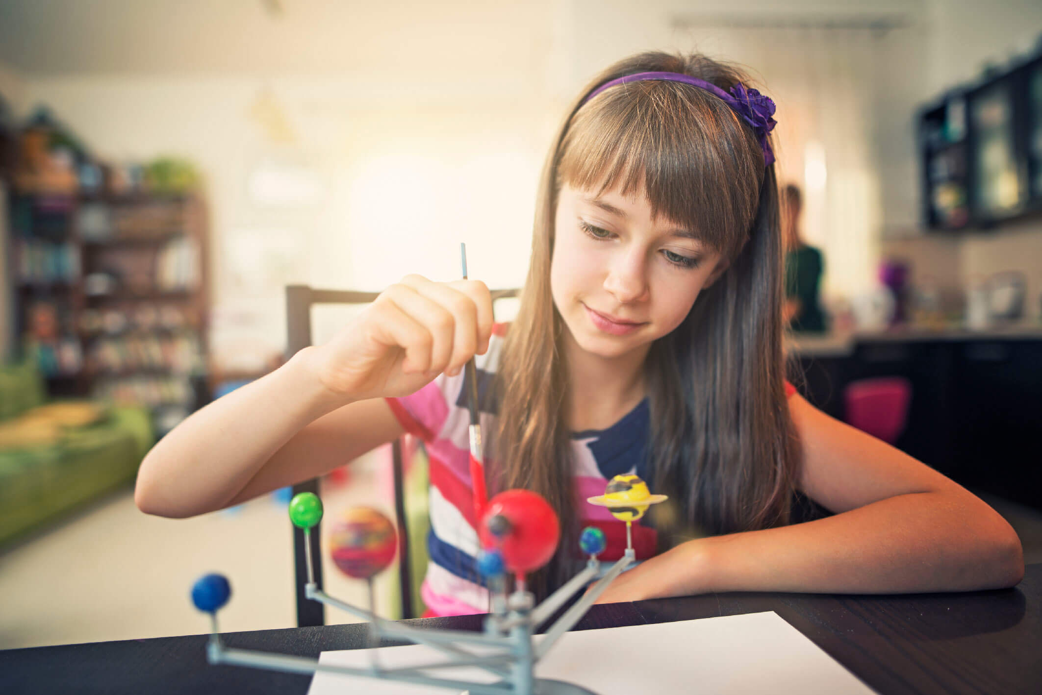 Little girl painting solar system model