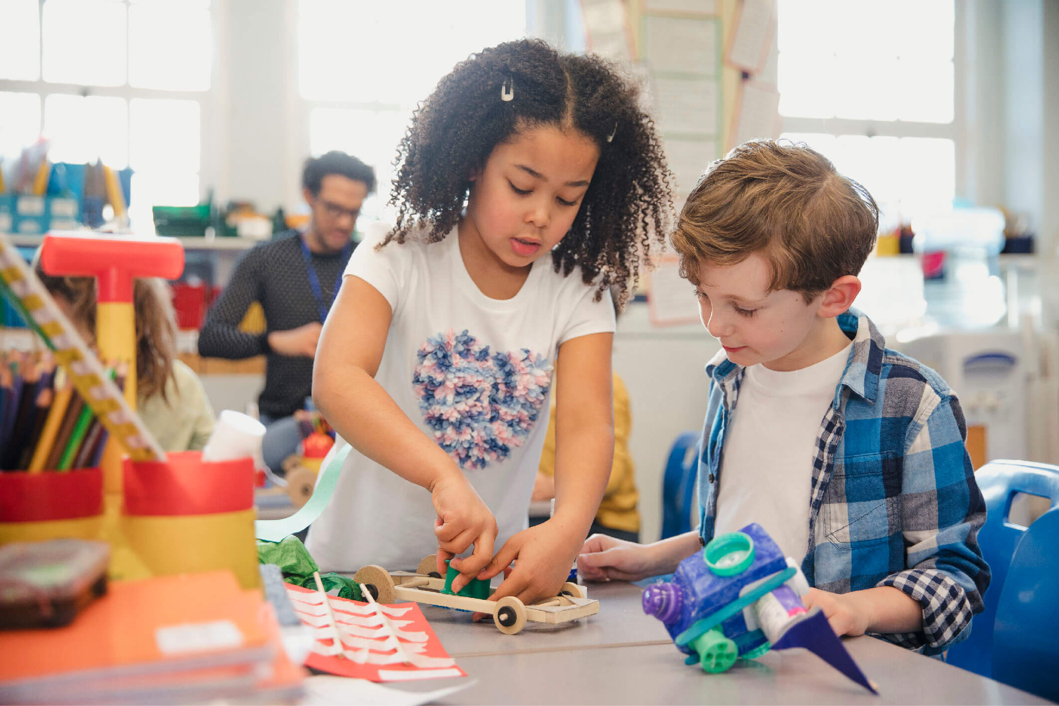 Elementary school children build 3d models using recycled materials during class.