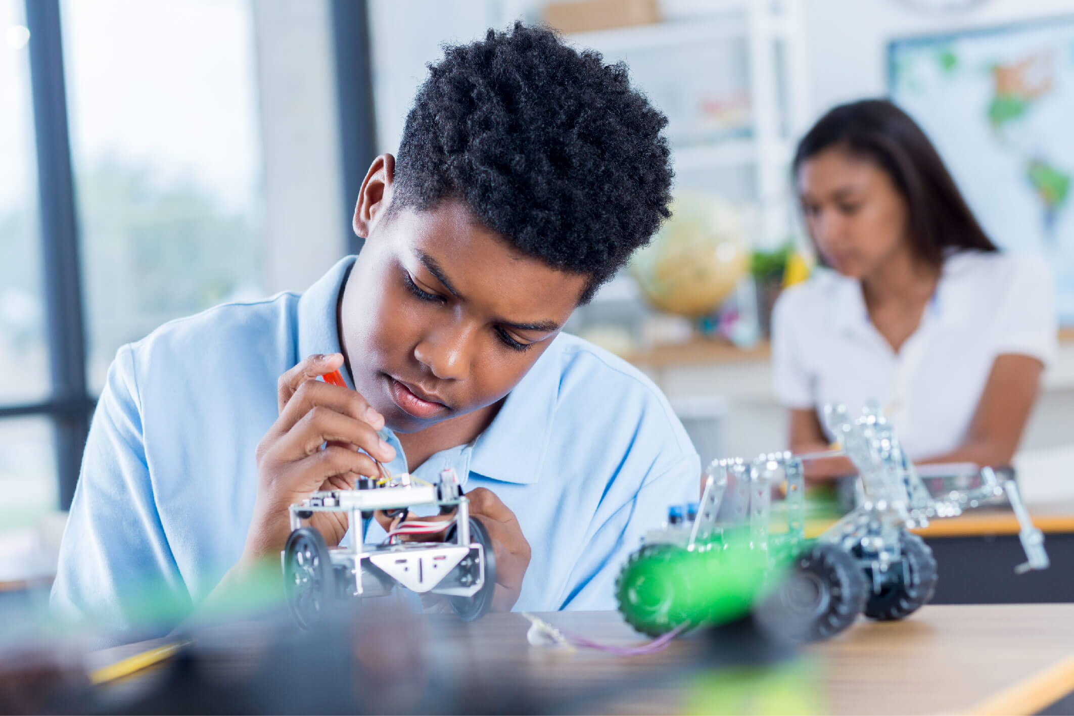 Focused teenage boy builds robot at school